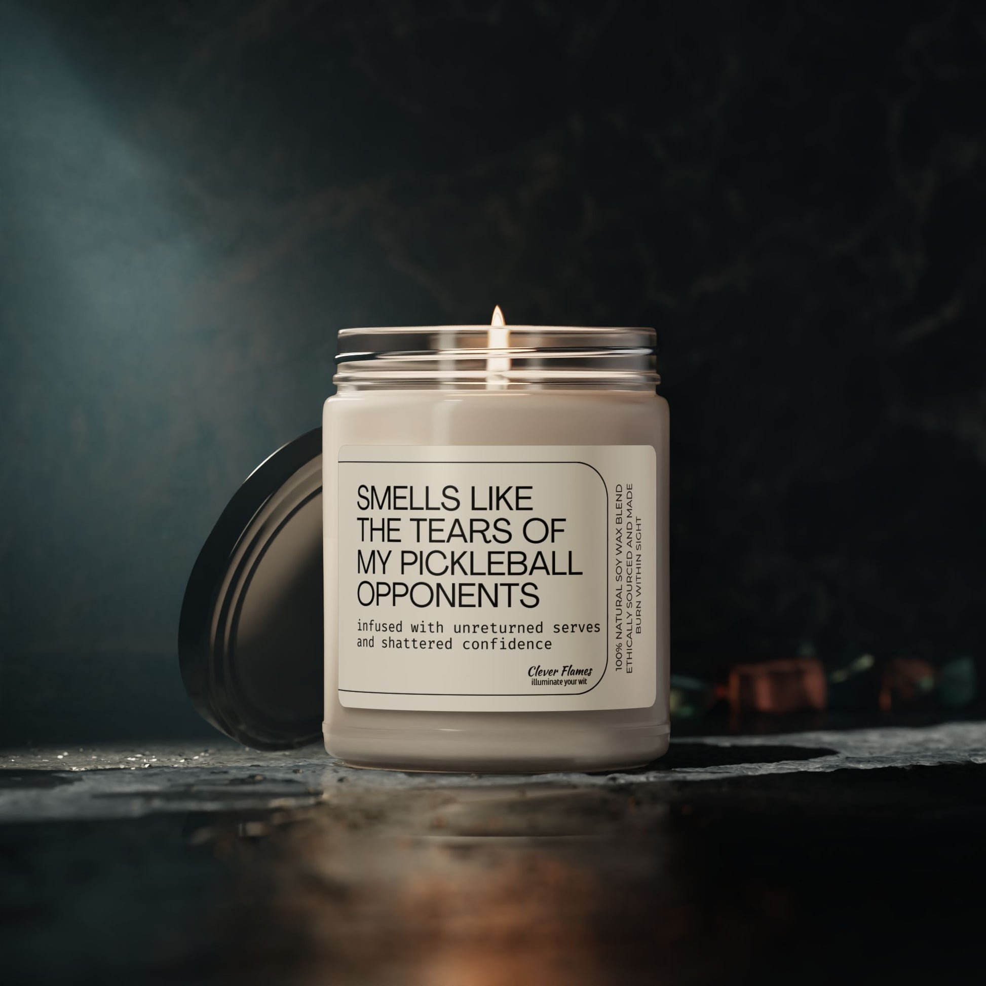 Printify’s Scented Soy Candle—“Smells Like the Tears of My Pickleball Opponents”—rests on a dark surface in its reusable glass jar, lid off; the perfect eco-friendly gift infused with humor for pickleball lovers.