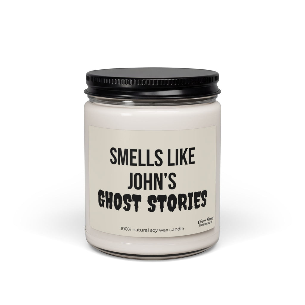 A personalized soy candle from Printify, featuring a white jar with a black lid and bold “Smells Like John’s Ghost Stories” text on the label. Ideal as Halloween or spooky fall room decor, the label at the bottom reads “100% natural soy wax candle.”.