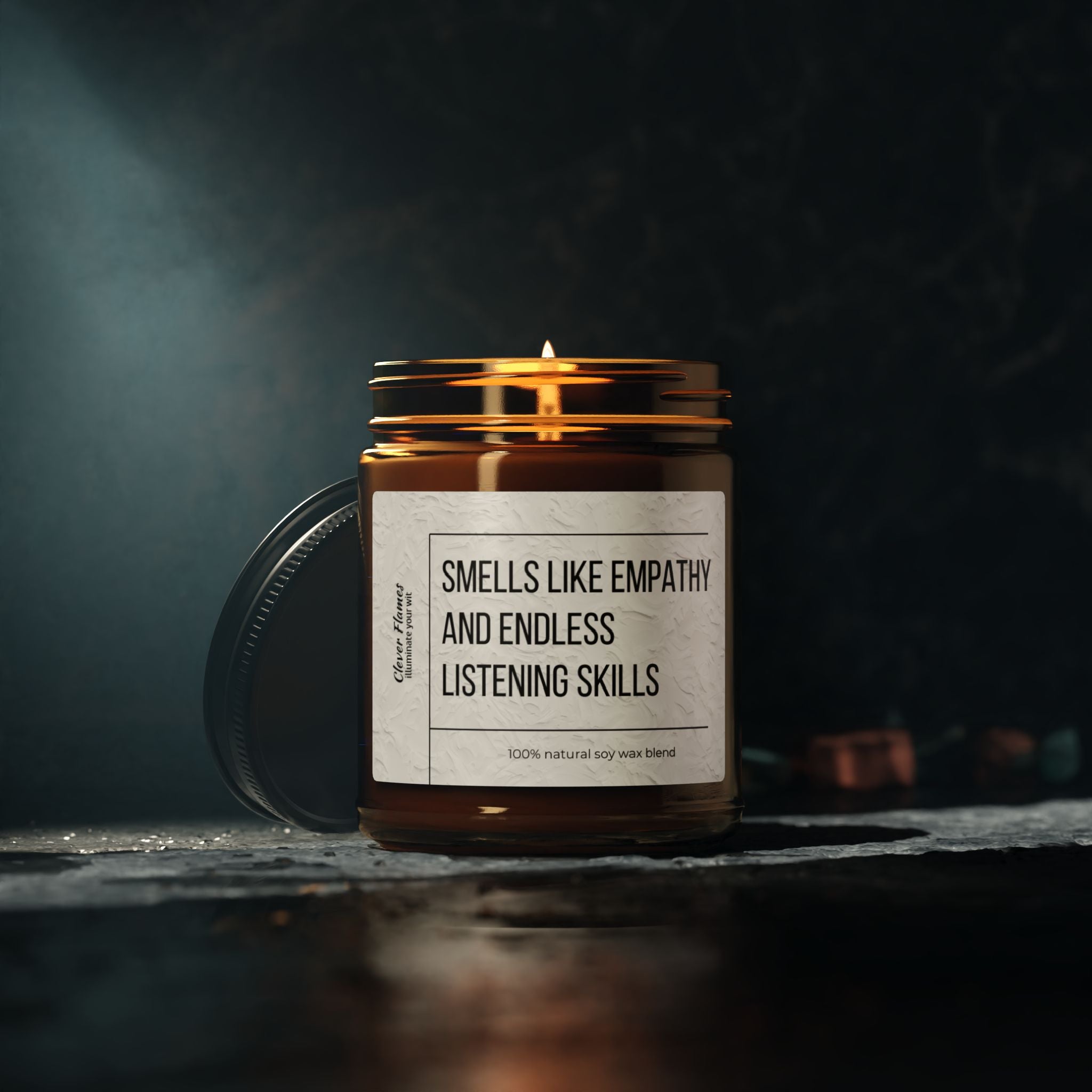 A lit candle in a glass jar rests on a dark surface, releasing a soothing fragrance. The label reads "Counselor Candle - Smells Like Empathy & Endless Listening Skills," making it an ideal gift for therapists, social workers, and mental health heroes. Made by Printify from 100% natural soy wax blend, this eco-friendly scented candle is set against a softly illuminated, blurred background.