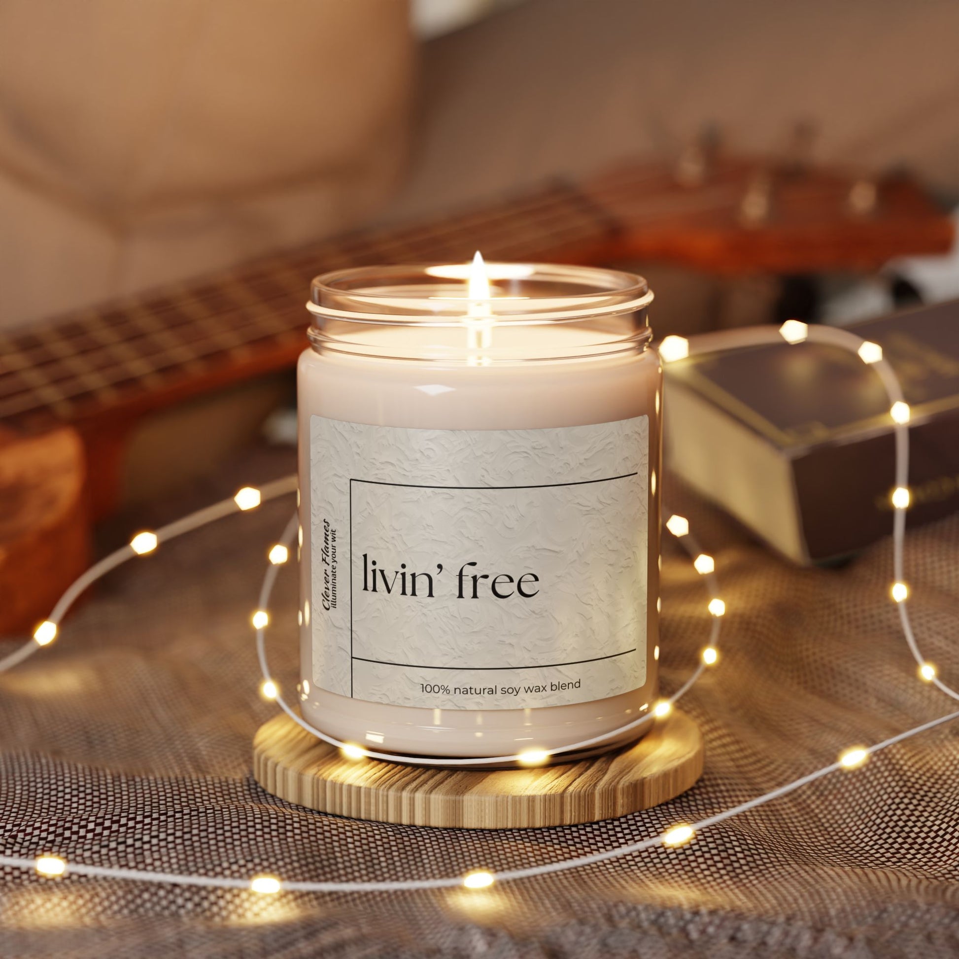 The Printify Livin’ Free Summer Break Candle – a funny teacher appreciation gift made from 100% natural soy wax – sits on a wooden coaster with string lights, perfect for summer vacation lovers.