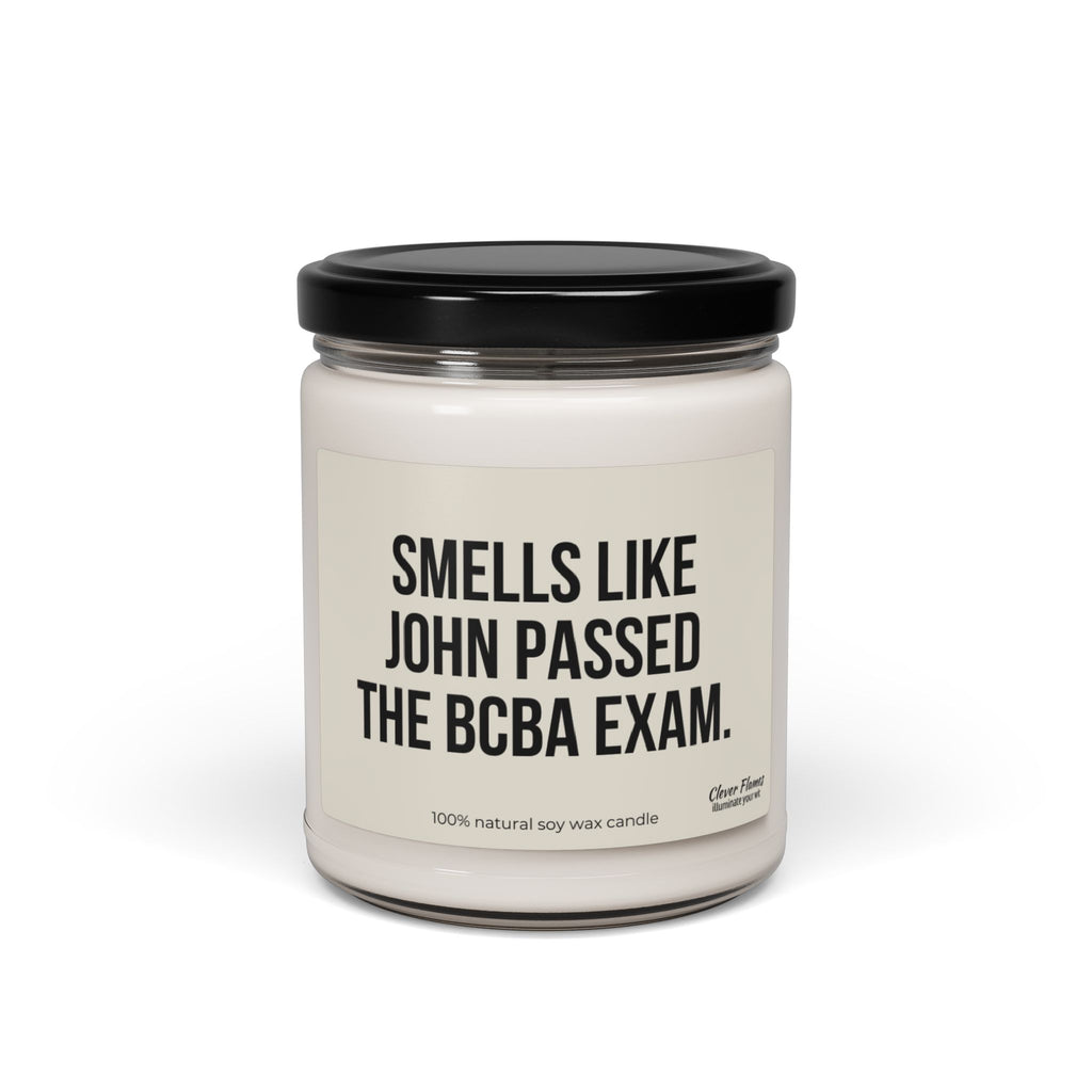 The Personalized Behavior Analyst Candle Gift by Printify features a white candle housed in a glass jar with a black lid and a striking label that reads, "Smells like John passed the BCBA exam." Made from a 100% natural soy wax blend, this minimalist design makes an ideal custom candle gift.
