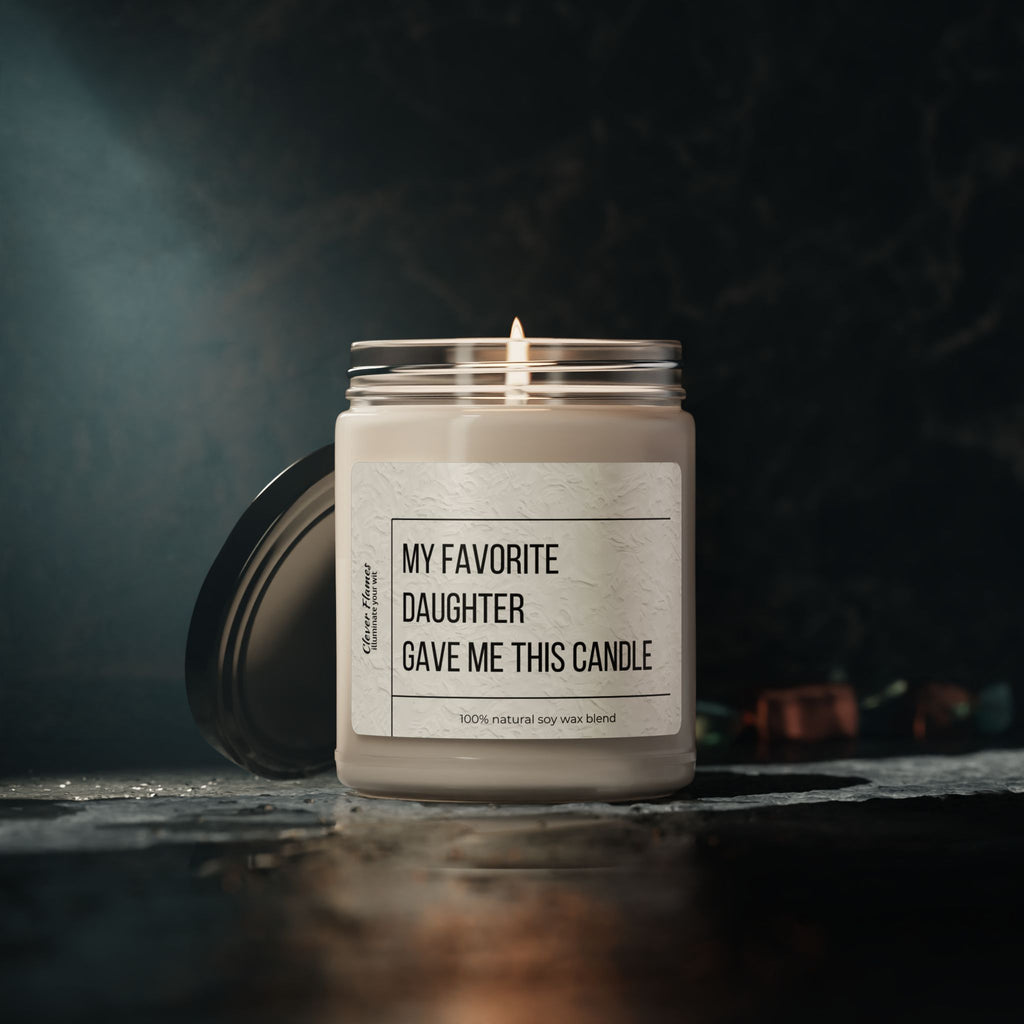 The Printify My Favorite Daughter Scented Soy Candle, 9oz, with a labeled glass jar and black lid, sits lit on a dark surface against a blurred background—ideal for birthdays, Mother’s Day, decor, relaxation, or celebrations.