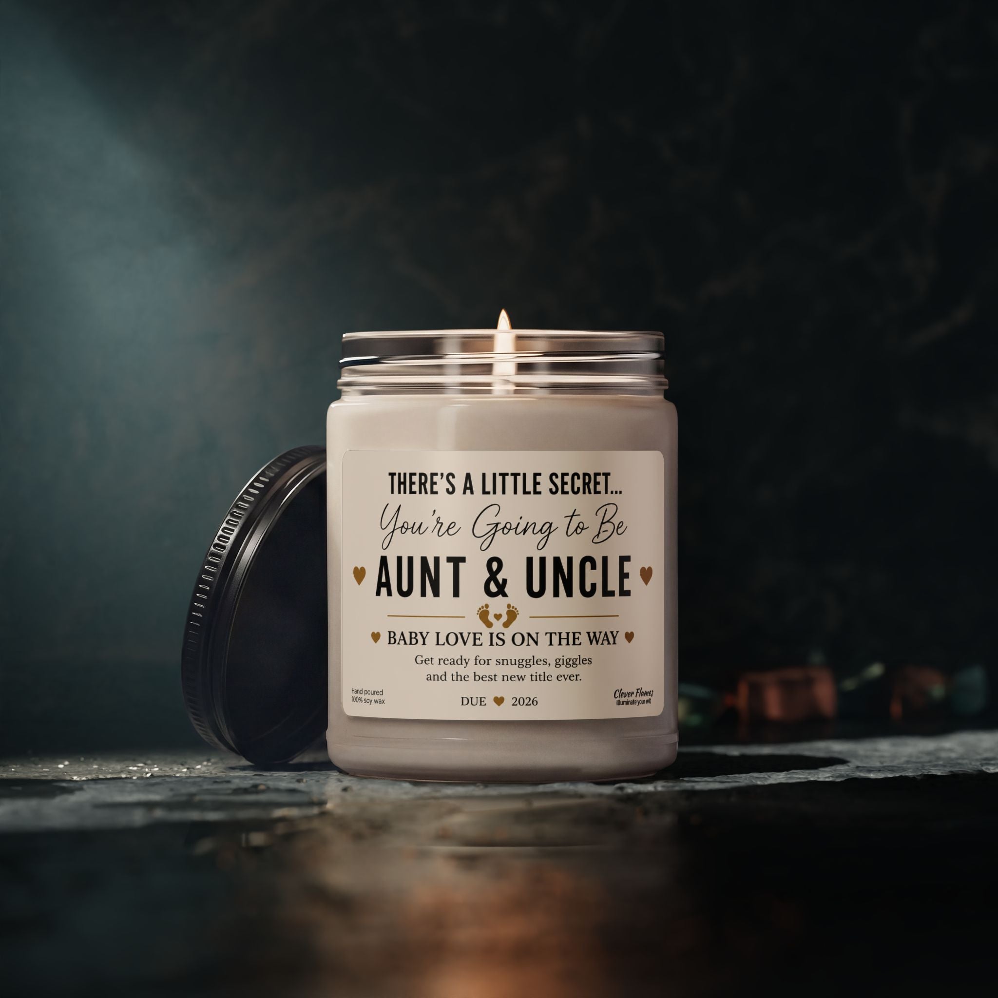 A glowing Printify Pregnancy Announcement for Aunt and Uncle Candle sits in its jar, displaying the heartfelt message: “You’re going to be Aunt & Uncle. Baby love is on the way.” The lid rests nearby, while a softly blurred dark background sets the scene for a perfect baby reveal gift and memorable announcement moment.