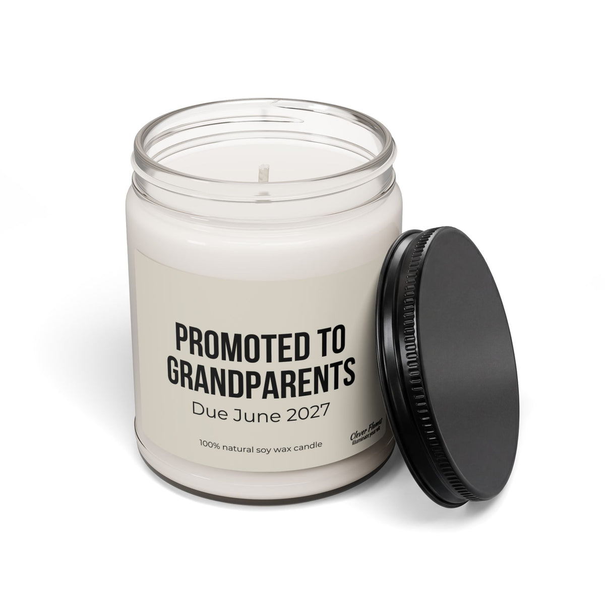 The Printify “Promoted to Grandparents 9oz Scented Soy Candle — ‘Due June 2027’ Pregnancy Announcement Gift” features a white, 100% natural soy wax candle in a reusable glass jar with a black lid. The label reads: PROMOTED TO GRANDPARENTS Due June 2027.