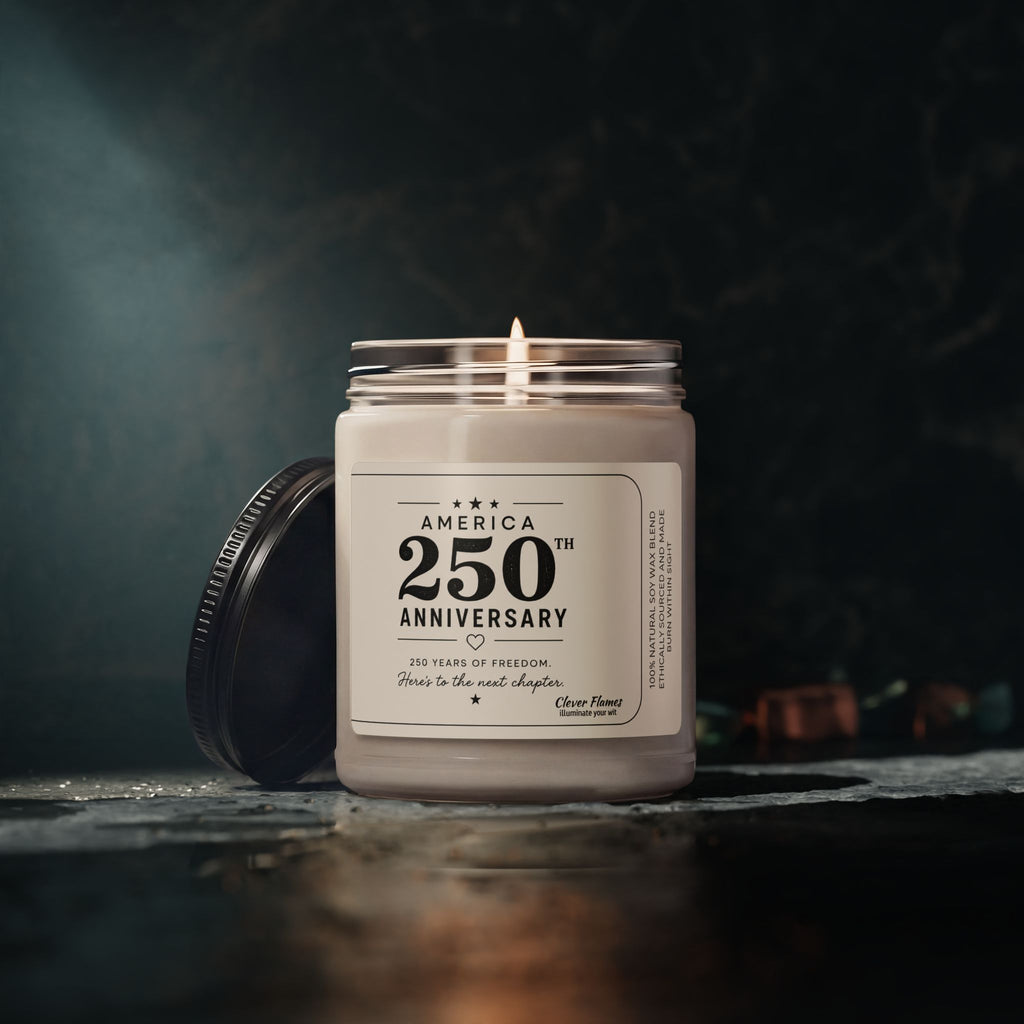 The Printify America 250th Anniversary Scented Soy Candle, 9oz, features a patriotic label and a removable black lid—perfect as a Semiquincentennial gift or for displaying your love of freedom. Shown lit in its glass jar against a dark, blurred background.