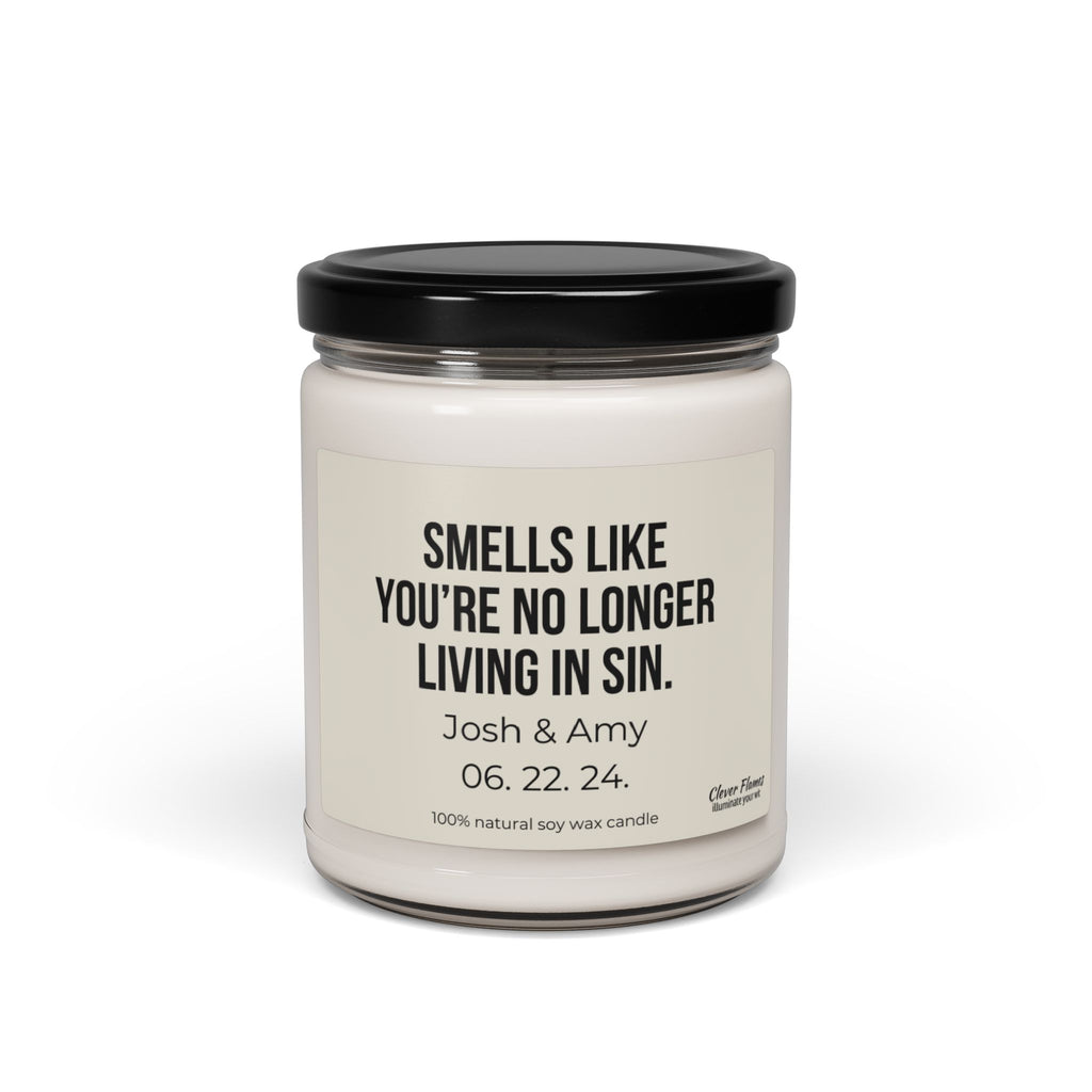 This white soy candle comes in a jar with a black lid and features the text "Smells like you’re no longer living in sin." Ideal for an engagement gift, it highlights the names Josh & Amy along with their date 06.22.24 and is made from 100% natural soy wax. The product is named "No Longer Living In Sin Soy Candle Custom Wedding Gift Funny Personalized Anniversary For Husband Engagement Date for Couple" by the brand Wedding.