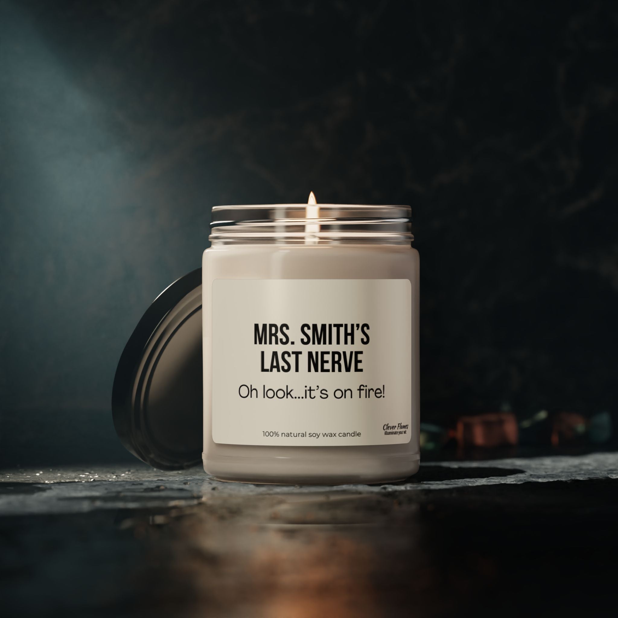 The "Teacher Appreciation Last Nerve Candle Personalized Gift for Back to School" by Printify humorously captures the vibe with its label, "Mrs. Smith's Last Nerve: Oh look...it's on fire!" Ideal as a teacher gift, this soy candle rests on a dark surface beside a slightly open black lid, adding both coziness and humor to any setting.