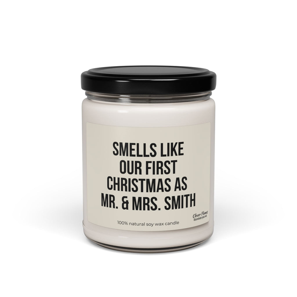 A personalized First Christmas candle from Printify, made of white soy wax in a glass jar with a black lid, is the perfect gift for newlyweds. The label says, "Smells like our first Christmas as Mr. & Mrs. Smith," making it an ideal choice for their first holiday together.