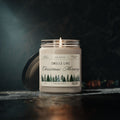 A 9oz Smells Like Christmas Morning – Holiday Soy Candle by Printify glows in a glass jar with pine tree illustrations and its black lid beside it, creating a cozy holiday atmosphere against a dark surface and blurred background.