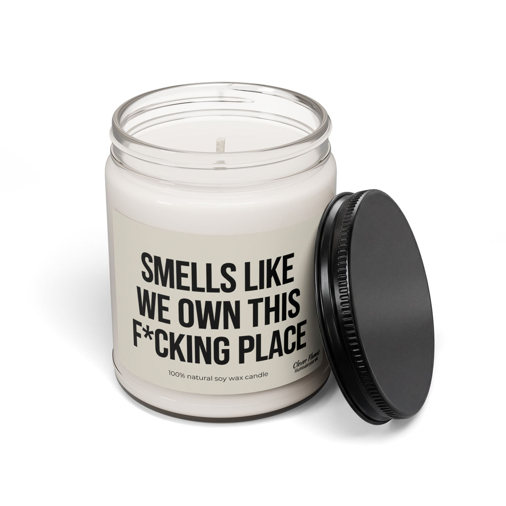 A Smells Like We Own This F*Cking Place Candle in a jar with a black lid, featuring a label that reads, Smells like we own this f*cking place.