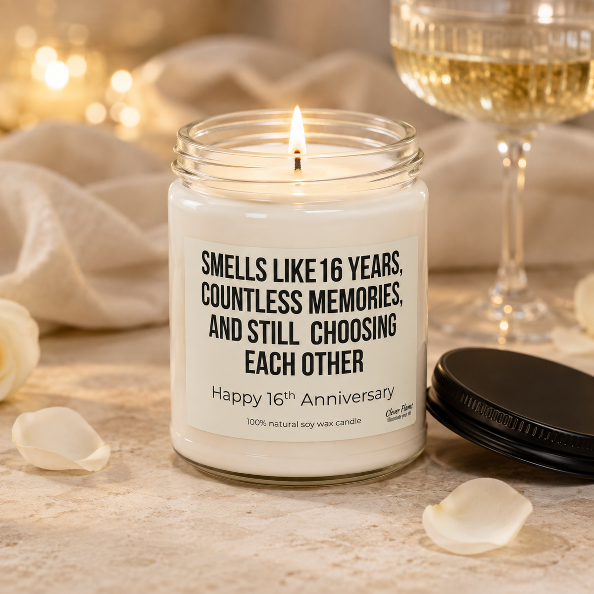 A glowing white candle from Printify sits in a glass jar, labeled: “Smells like 16 years, countless memories, and still choosing each other. Happy 16th Anniversary.” This elegant 16th Anniversary Candle—an ideal wax anniversary gift for your wife or husband—is beautifully displayed among rose petals and a drink, with soft lights illuminating the background.