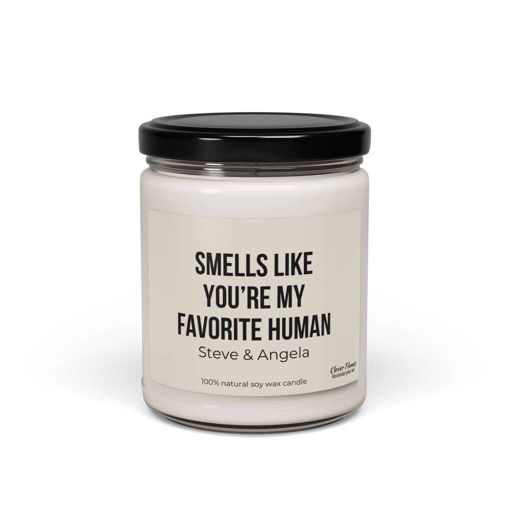 A white soy wax scented candle housed in a clear jar with a black lid features the label "Smells like you're my favorite human" by Printify, making it an ideal personalized anniversary gift.
