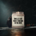 A lit Smells Like There’S Two Buns In The Oven Custom Candle For Twins Pregnancy Announcement in a glass jar, used as a playful twin pregnancy announcement gift.