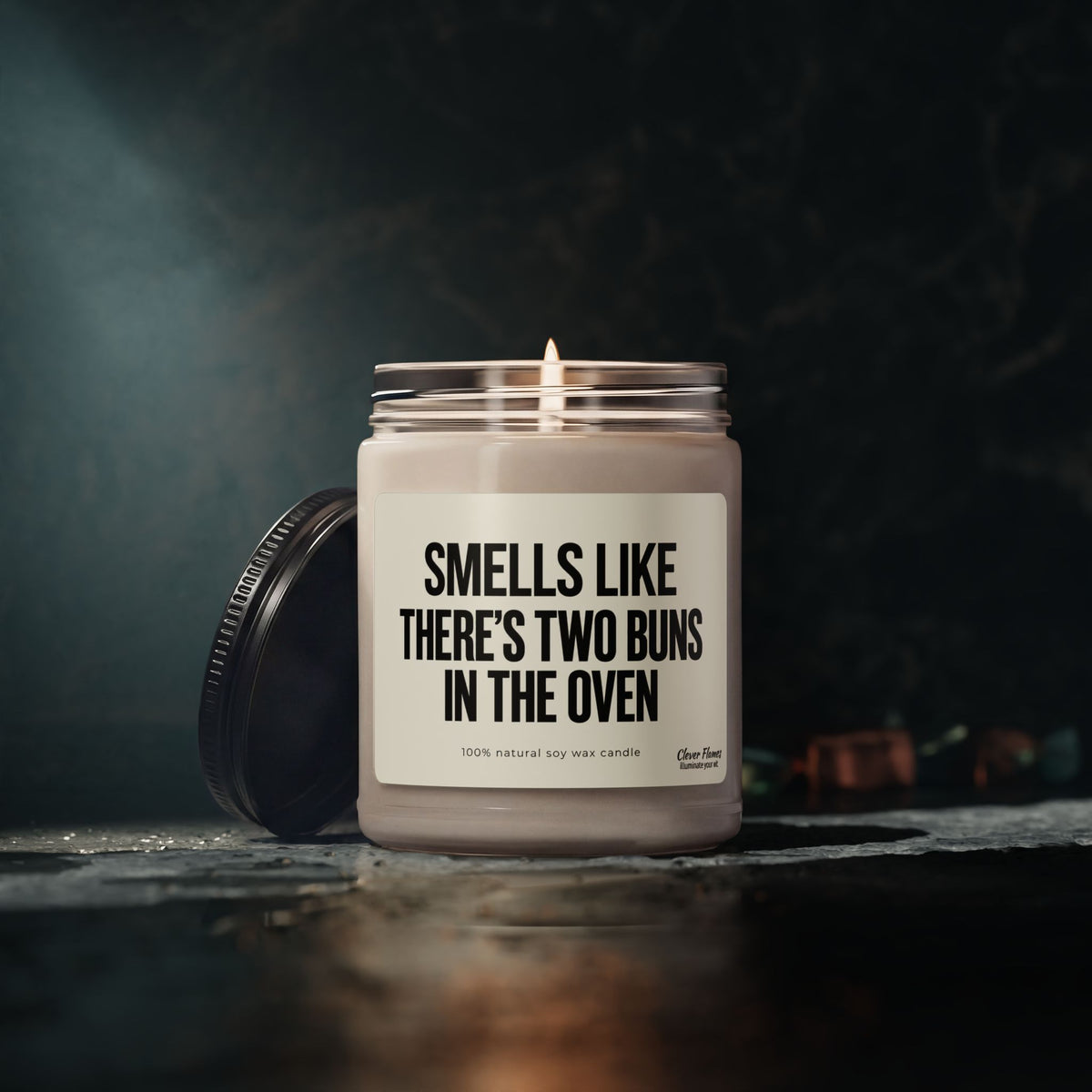 A lit Smells Like There’S Two Buns In The Oven Custom Candle For Twins Pregnancy Announcement in a glass jar, used as a playful twin pregnancy announcement gift.