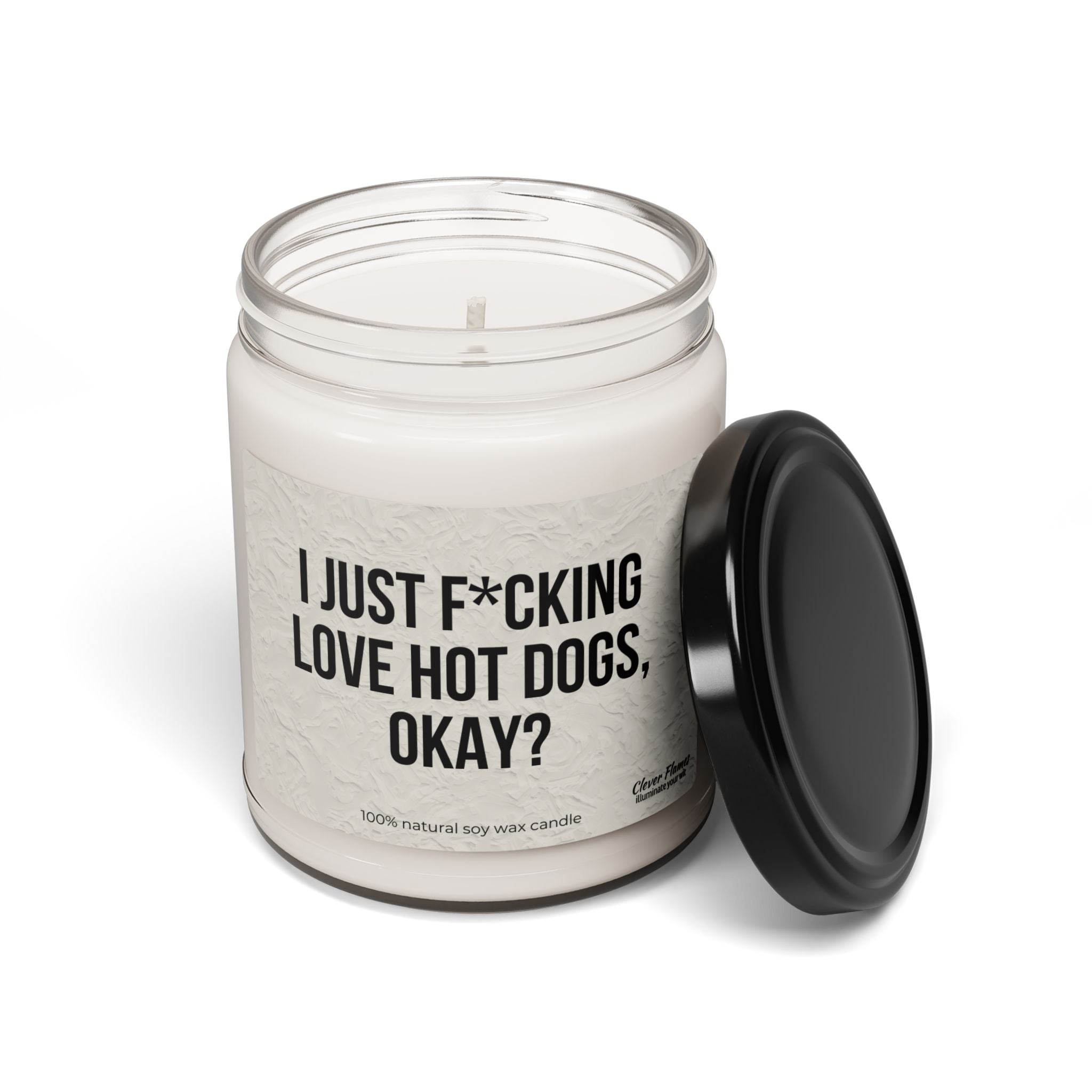 The Printify "I Just F*cking Love Hot Dogs Okay?" Candle is a 9oz scented soy candle in a reusable glass jar with black lid, featuring the bold phrase on its label.