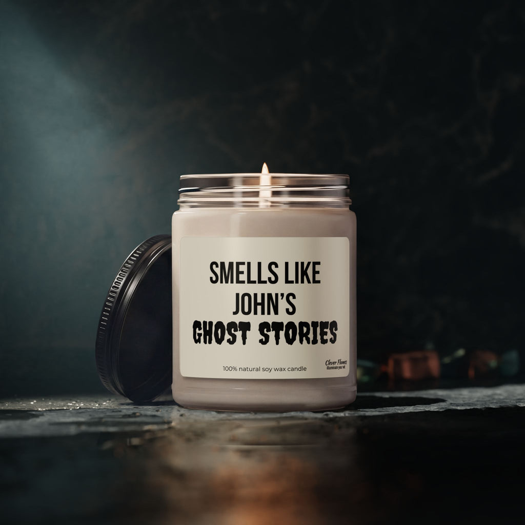 A lit Printify Personalized Ghost Stories Soy Halloween Candle Gift for Spooky Decor for Fall October Holiday Room sits in a glass jar on a dark surface, its lid resting nearby. The candle’s soft glow creates an eerie ambiance against the dim, blurred background—perfect for adding unique Halloween flair to your space.