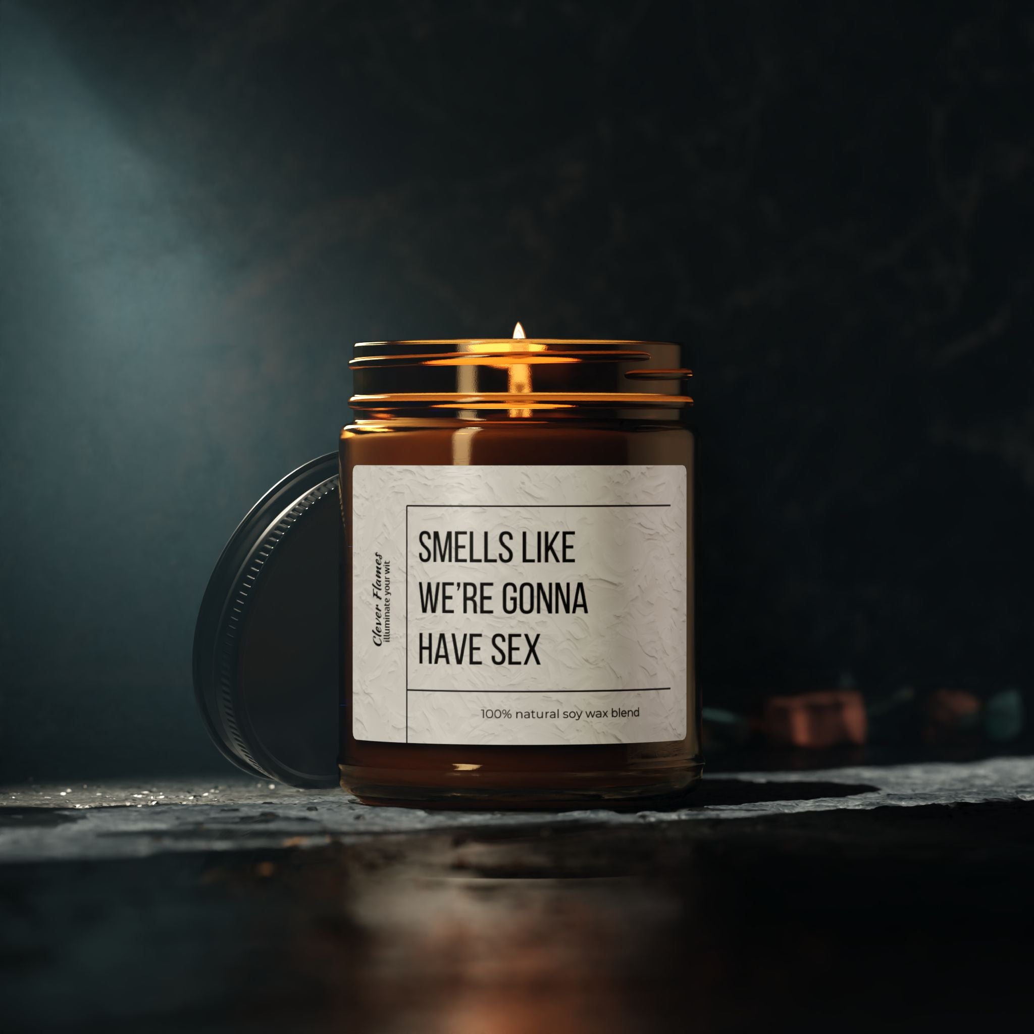 A Printify Smells Like Were Gonna Have Sex candle in a brown jar sits on a dark surface, side-lit. Made from an eco-friendly, reusable glass vessel, its lid leans casually beside it, enhancing the allure of this intimate scented gift for her or him.