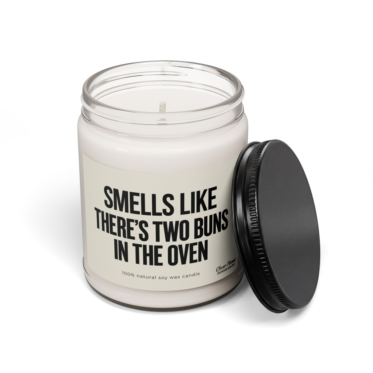 A Smells Like There’S Two Buns In The Oven Custom Candle For Twins Pregnancy Announcement in a glass jar with a black lid and a label reading, Smells like there’s two buns in the oven.
