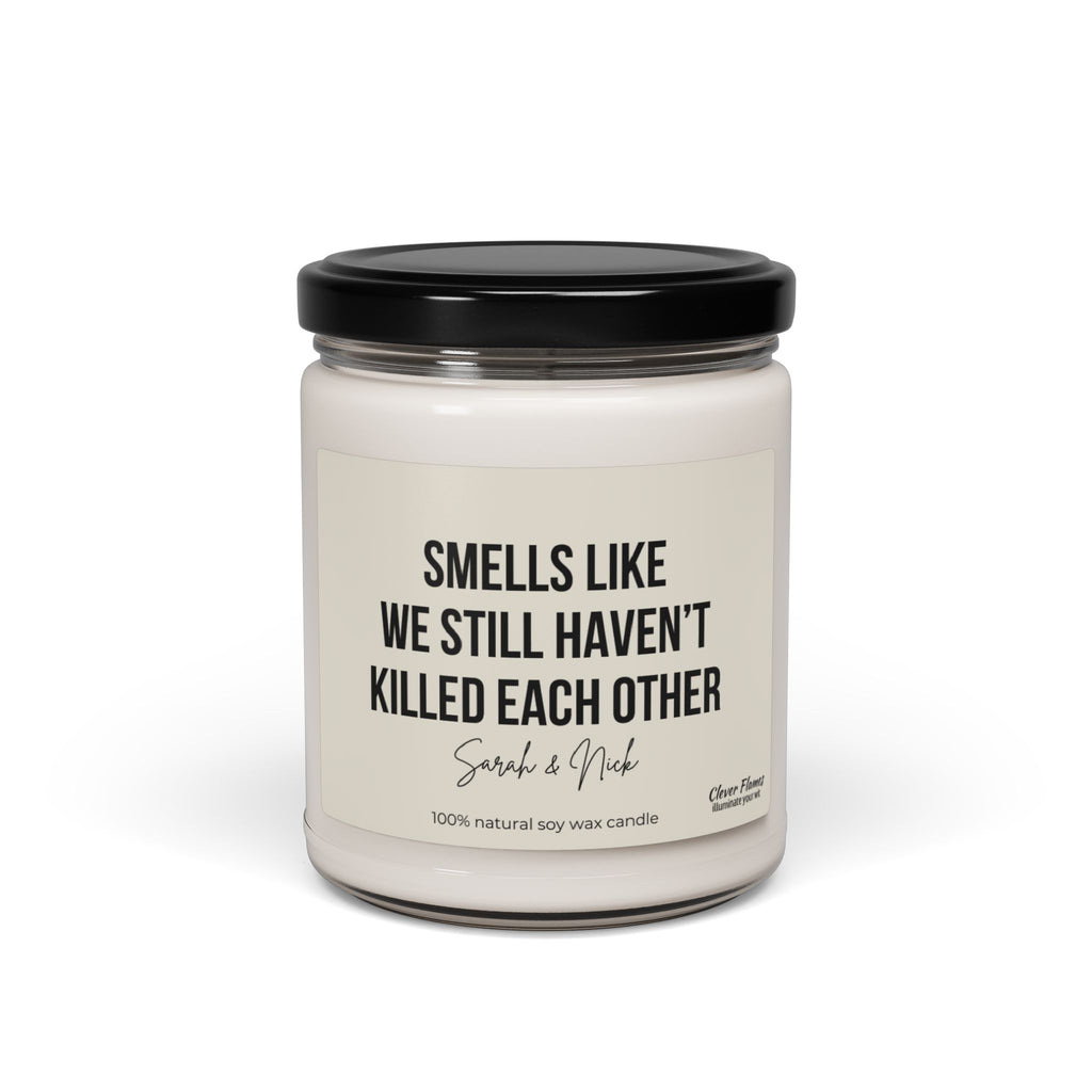 A personalized anniversary candle by Wedding, featuring a humorous message that reads "Smells like we still haven’t killed each other," is crafted from 100% natural soy wax. This white candle comes in a glass jar with a black lid and makes an excellent gift for friends, husbands, wives, birthdays, or Valentine's Day.