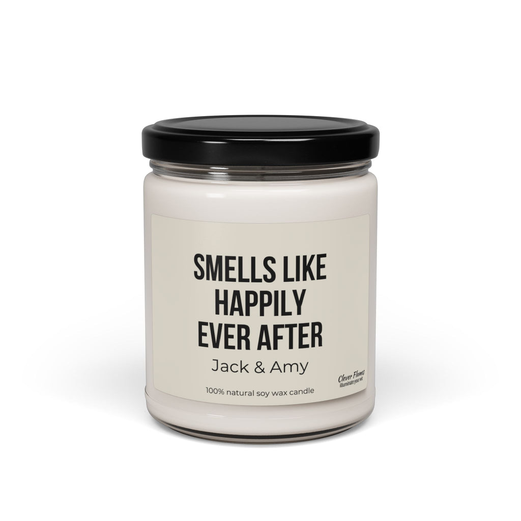 A personalized gift for weddings, this product is a white soy wax candle housed in a clear glass jar with a sleek black lid. The label features the message, "Smells Like Happily Ever After, Jack & Amy," making it an ideal custom wedding gift. Crafted from 100% natural soy wax, this candle includes subtle branding by Wedding in the bottom right corner.