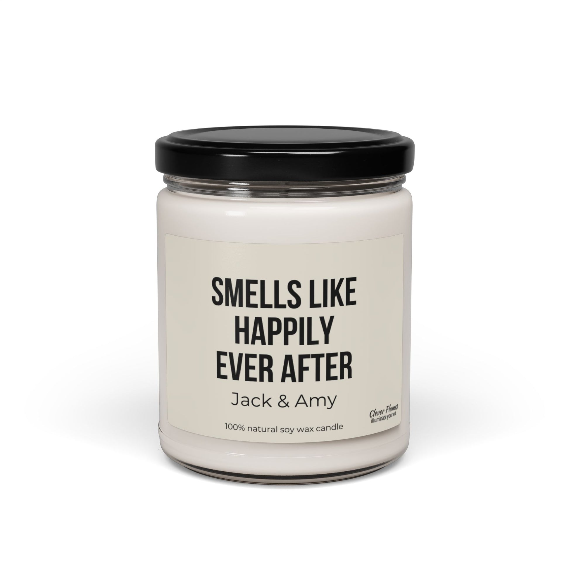 A personalized gift for weddings, this product is a white soy wax candle housed in a clear glass jar with a sleek black lid. The label features the message, "Smells Like Happily Ever After, Jack & Amy," making it an ideal custom wedding gift. Crafted from 100% natural soy wax, this candle includes subtle branding by Wedding in the bottom right corner.