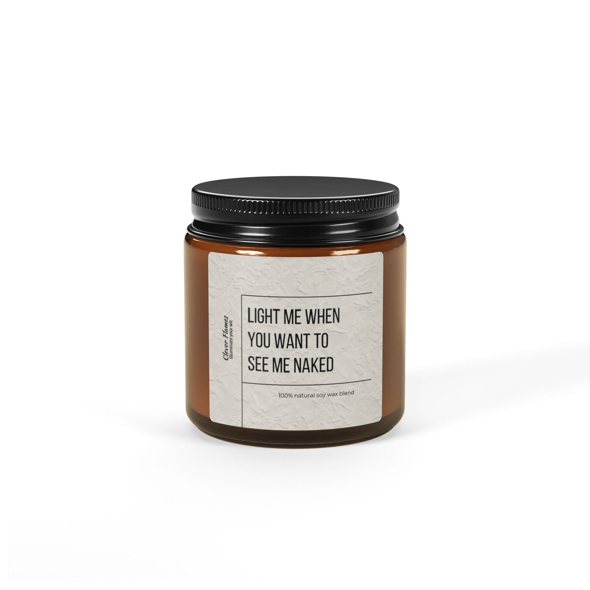 A brown scented soy candle from Printify, housed in a glass jar with a black lid. The label humorously reads, "LIGHT ME WHEN YOU WANT TO SEE ME NAKED," emphasizing its 100% natural soy wax blend. Its minimalist design against a plain white background makes it an ideal choice for setting a romantic mood or as a playful Valentine's Day gift.