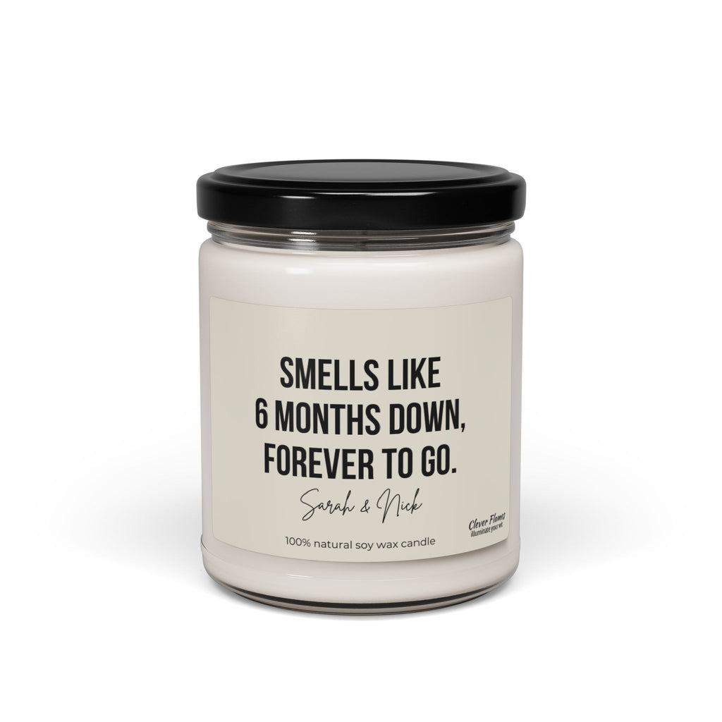 A personalized 6-month anniversary candle, crafted by Wedding from 100% natural soy wax, showcases a white jar with a black lid featuring the text: Smells like 6 months down, forever to go. Sarah & Nick. It's an ideal gift for friends or partners and adds a memorable, fragrant touch to any celebration.