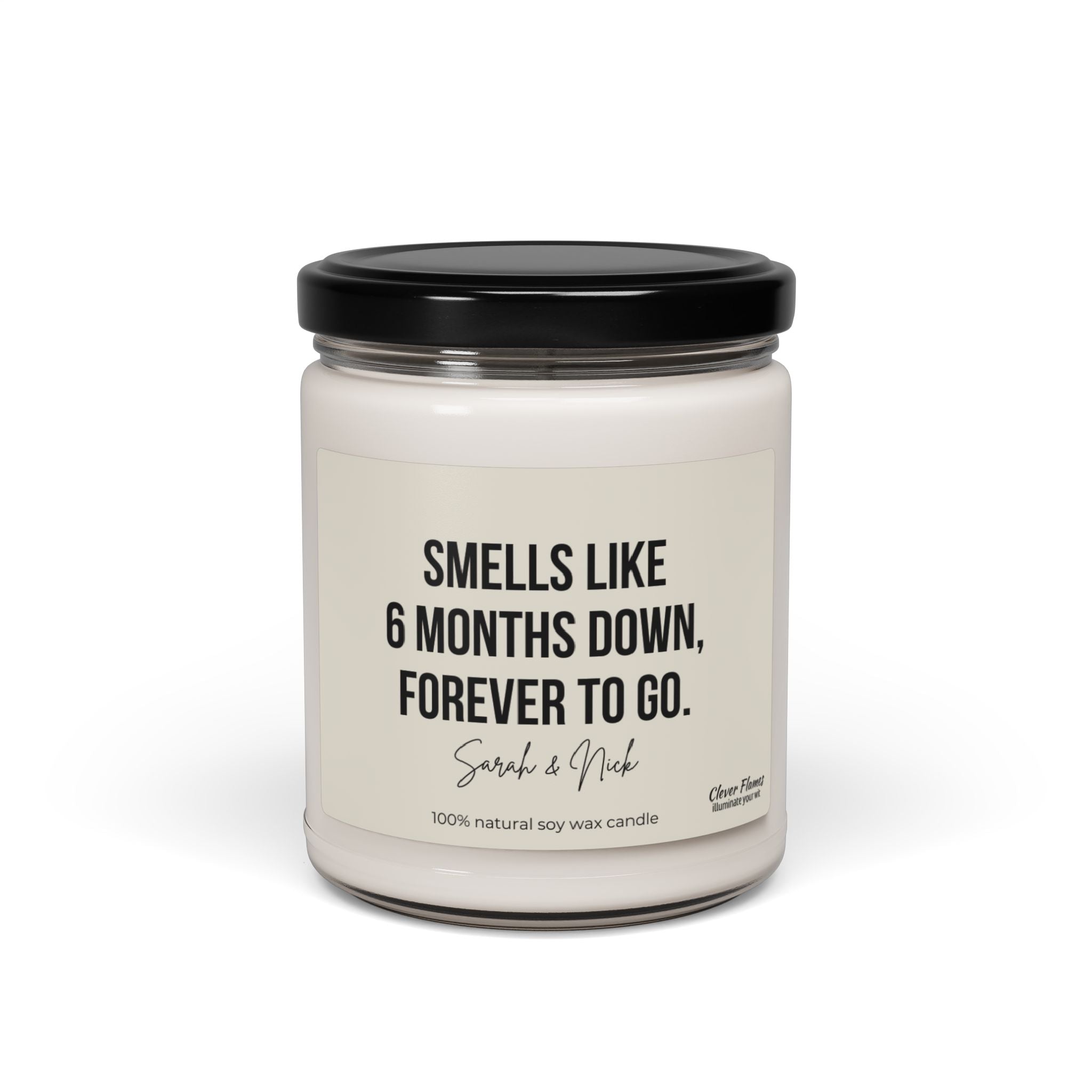 A personalized 6-month anniversary candle, crafted by Wedding from 100% natural soy wax, showcases a white jar with a black lid featuring the text: Smells like 6 months down, forever to go. Sarah & Nick. It's an ideal gift for friends or partners and adds a memorable, fragrant touch to any celebration.