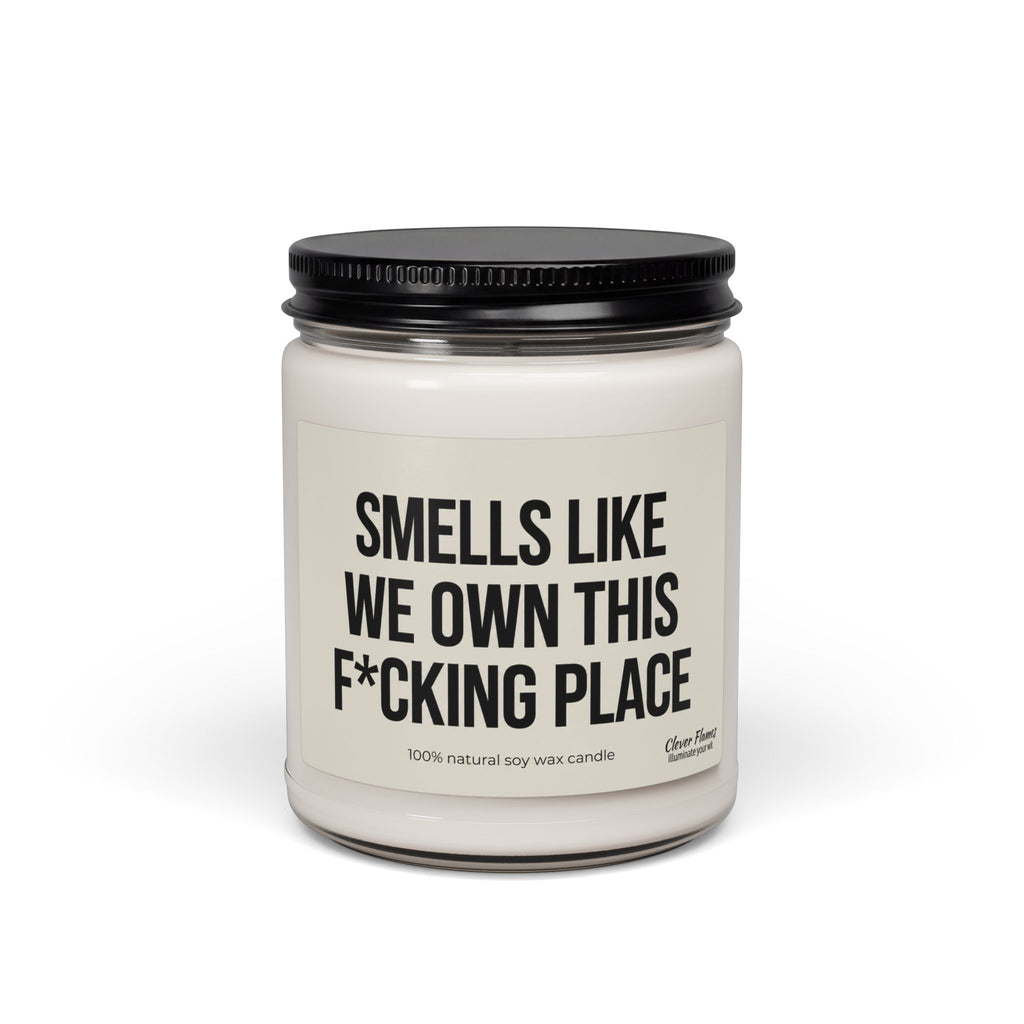 Glass candle jar with a black lid and a label for a Smells Like We Own This F*Cking Place Candle, making it a bold housewarming gift.