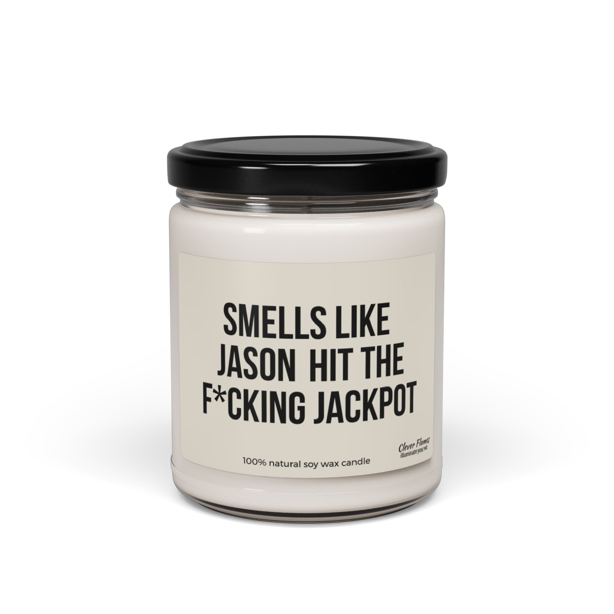 A personalized engagement candle from the brand Wedding, featuring a glass jar with a black lid. The label humorously states: "Smells like he hit the jackpot," and it's crafted from 100% natural soy wax—perfect as a funny custom engagement gift.