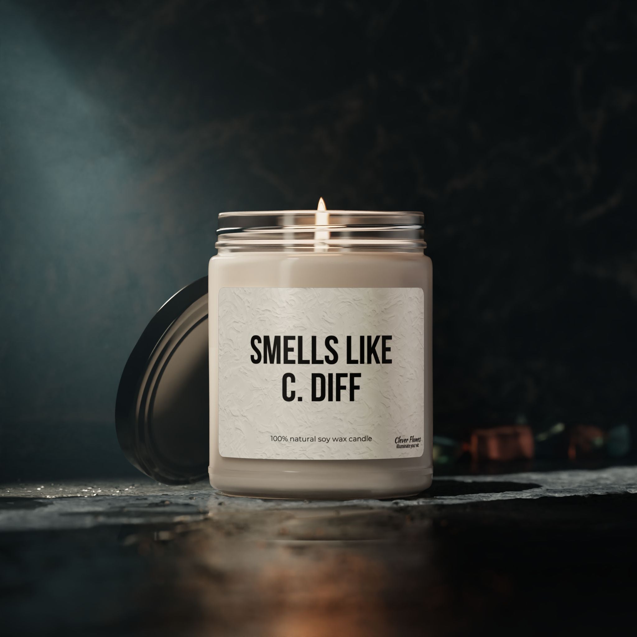 Printifys Smells Like C. Diff candle, a funny gift for nurses, features a black lid and white text reading 100% natural soy wax candle. It adds healthcare humor and a moody ambiance to any space, making it an ideal medical gag gift for healthcare workers.