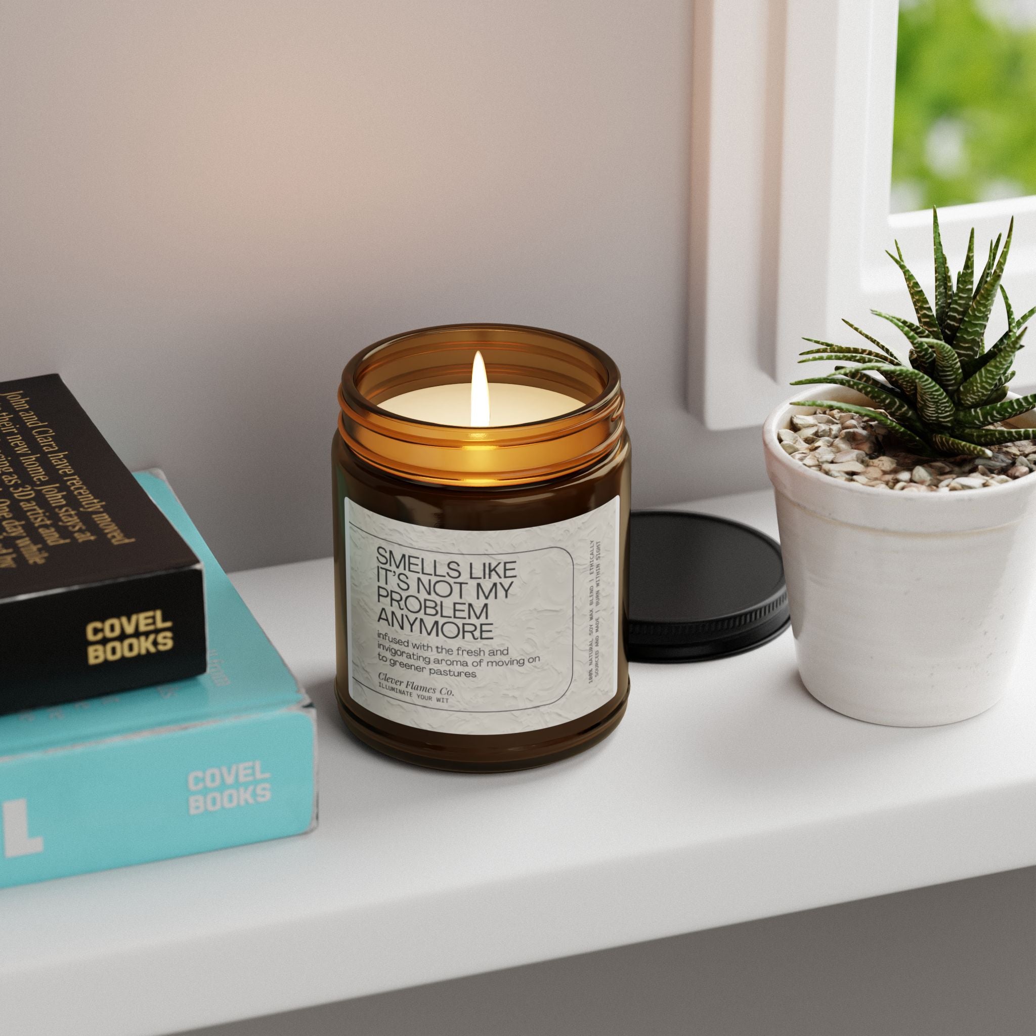 A lit brown jar candle with a white label is placed next to a small potted succulent and stacked books on a white shelf. The label reads, "Not My Problem Anymore," capturing the theme of retirement joy through Printify's Funny Retirement Scented Soy Candle with its captivating Atlantis Whisper fragrance.